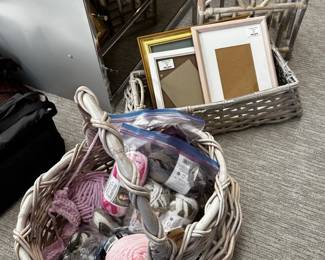 A wicker basket with handle, skeins of wool, picture frames, and a vintage bamboo and rattan magazine rack
