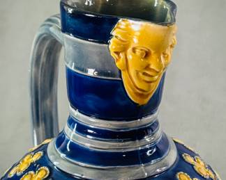 Closeup of the English majolica pitcher by Minton circa 1871, moulded ovoid body in a cobalt blue ground and raised deep yellow quatrefoil florets, loop handle rising to a masked spout; incised Minton mark, incised style #596, incised #12, incised date code (NC).   