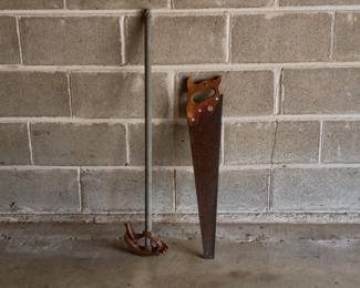 A vintage handsaw and manual conduit pipe bender