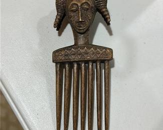 A vintage decorative African wooden comb, often referred to as a Luba or Ashanti style hair pick, featuring a carved human figure or face on the handle
