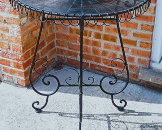 A vintage-style black wrought iron demilune (half-moon) accent table or plant stand