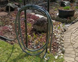 A wrought iron garden hose holder