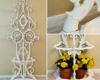 A vintage painted cast iron hall tree with a white finish, ornate scrollwork, upper hooks for coats, and a base designed to hold umbrellas.