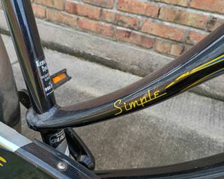 Closeup of the Giant Simple cruiser bike, featuring a distinct black frame decorated with yellow and blue flame graphics and chrome fenders