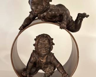 A decorative sculpture in the style of Joan Clarà Olot, depicting two children at play.