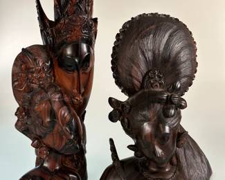 Two Balinese hand-carved wooden sculptures, one depicting a pair of faces, likely representing characters from Indonesian folklore such as Rama and Sita; the other a carved hardwood bust depicting a goddess or dancer.