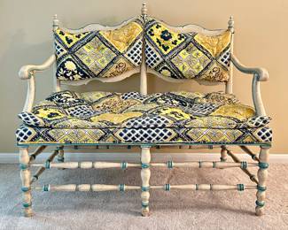 A vintage-style settee with painted cream and teal frame and floral fabric cushions