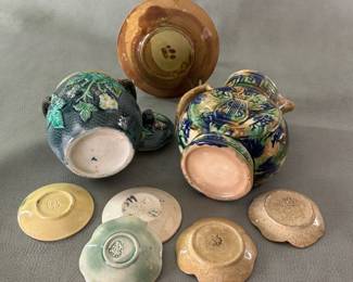 Reverse view of antique and vintage majolica including Griffin, Smith & Hill butter pats, a lidded jam jar with blackberry pattern and finial, and a circa 1885-90 American majolica ware cream pitcher, 6" high, unusual jug with Greek key fret decoration around the neck, high relief lyre/musical instruments on the body; hand-painted in blue, brown, green and mauve applied in dabbing streaking manner, pale lavender liner.