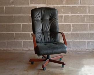 An executive-style office chair with a high-back tufted leather seat, wood finish armrests, and a swivel base with casters.