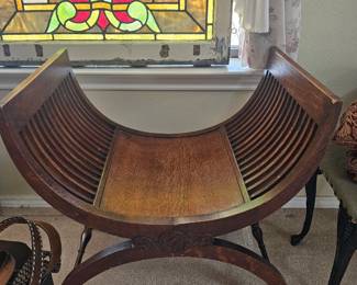 A wooden Jugendstil gondola stool with slatted seat and carved stretcher.