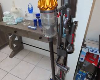 Dyson stick vacuum with charging stand and attachments.