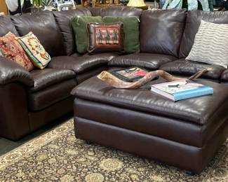 Brown leather sectional with matching ottoman, books galore in background