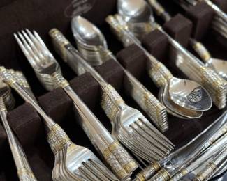 Elegant Wallace Sterling Silver flatware in the “Golden Aegean Weave” pattern, a striking design introduced in 1971 featuring an intricate woven texture accented with warm gold detailing. This pattern beautifully blends classic sterling craftsmanship with a distinctive mid-century luxury aesthetic.
The set is presented in its fitted wooden buffet chest and includes a generous assortment of serving pieces and place settings. The rich woven motif with gold accents adds visual depth and refinement, making it ideal for both formal entertaining and collectors of fine American sterling.