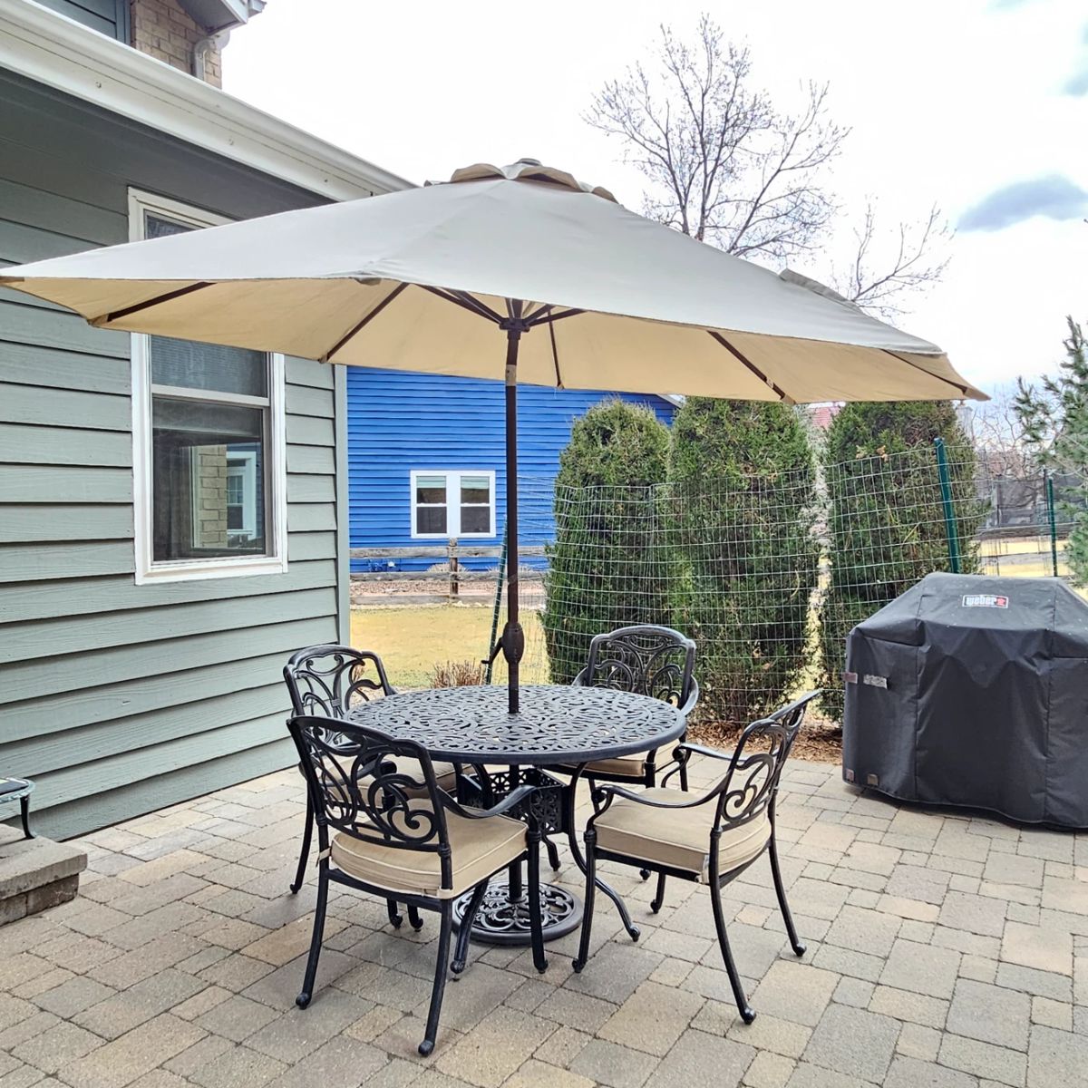Round Black Iron Patio Table Set with 4 Chairs, Cushions, and Beige Umbrella 48" Diameter