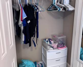 Walk-in closet with clothing, white 3-drawer organizer, trophies