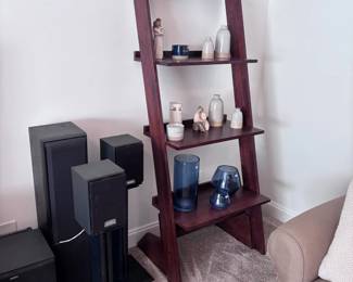 Dark wood ladder shelf with decor, surround sound speakers