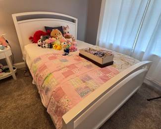 White twin bed frame with floral quilt and stuffed animals