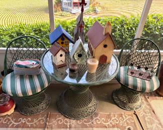Decorative birdhouses, wire patio chairs, glass table, garden decor