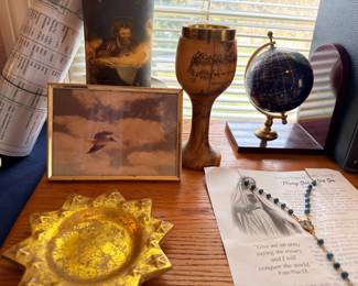 Decorative globe on brass stand, rosary, brass chalice, amber glass