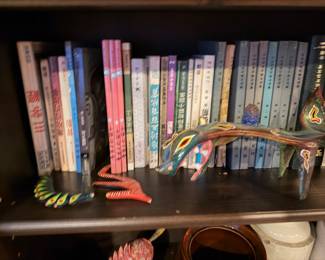 Oaxacan Dragon Alebrije: A long, hand-painted Mexican folk art sculpture featuring a green and brown serpent-like body Price: $195.00 |  Vintage Chinese Language Hardcover Collection: A set of approximately 14 uniform grey-bound volumes with blue spine labels, featuring classical Chinese titles and red stamps. Price: $120.00 (Set) | Assorted Books 