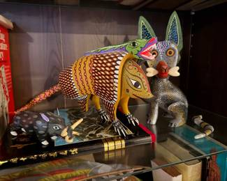 ntricate Armadillo Alebrije: A detailed, hand-painted Mexican folk art sculpture $185.00 | Unique Horned/Tusked Boar Alebrije: A whimsical small-scale folk art boar figure, uniquely detailed with large upward-curving horns/tusks, displayed on a black and gold book. Price: $110.00 | Whimsical Blue Dog/Coyote Alebrije: A charming folk art figure of a coyote or dog, featuring a blue patterned body and distinctive large ears. Price: $160.00 