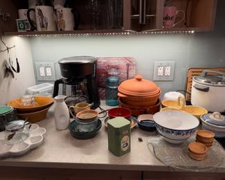 Mid-Century Green Brutalist Bowl: A heavy, textured ceramic bowl in deep olive green  $40 | White Ceramic Scalloped Serving Platter: A unique, flower-shaped divided porcelain dish   $40 | Brown Nesting Mixing Bowls: A set of two vintage-style ceramic mixing bowls with a warm yellow glaze and wide rims set $50 | Plastic Tupperware $20 each | White Textured Ceramic Sake Carafe $30 | Mr Coffee Coffee Maker $30 | Small ceramic bowls & Saucers $25 each | Terracotta Lidded Dutch Oven:&nbsp;A traditional unglazed clay cooking pot&nbsp; $85 | Blue-and-White Floral Porcelain Bowl: $35 | Artisanal Bamboo Oval Dipping Bowls $22  