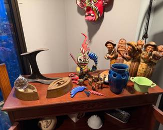 Left to Right: Mrs. Potts SadIron, cast-iron model developed in the 1870 2 pieces $50 each |  Cast Iron Cobbler’s Shoe Last: An authentic, heavy black cast iron anvil used for traditional shoemaking. Price: $90.00 |  Whimsical Alebrije-Style Creature: A vibrantly hand-painted folk art figurine with bulging eyes, blue wings, and a red spiked tail. Price: $75.00 | Brass Llama Family: A set of seven miniature brass llamas, often used as traditional South American good luck charms. Price: $60.00 total | Deep Blue Glazed Ceramic Vase: A cylindrical vessel featuring a rich cobalt glaze and a ring of decorative circular perforations near the rim. Price: $45.00 | Mint Green Ceramic Pot:  glazed ceramic container with dual handles. Price: $30.00 | Andean Folk Musician Group: hand-carved and painted wooden sculpture depicting a row of six musicians in traditional attire playing various instruments. Price: $145.00   