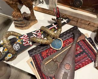 Bottle Cap Snake Sculpture flexible folk art sculpture made from numerous gold-colored metal bottle caps strung together. It features a hand-carved wooden head signed by "Simon 2004" $350, Teardrop-shaped wooden instrument with small circle inlay for striking $80   