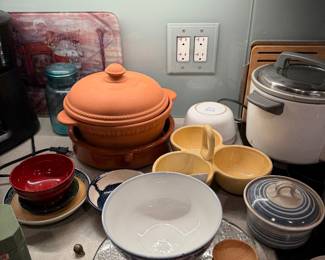 Mid-Century Green Brutalist Bowl: A heavy, textured ceramic bowl in deep olive green  $40 | White Ceramic Scalloped Serving Platter: A unique, flower-shaped divided porcelain dish   $40 | Brown Nesting Mixing Bowls: A set of two vintage-style ceramic mixing bowls with a warm yellow glaze and wide rims set $50 | Plastic Tupperware $20 each | White Textured Ceramic Sake Carafe $30 | Mr Coffee Coffee Maker $30 | Small ceramic bowls & Saucers $25 each | Terracotta Lidded Dutch Oven:&nbsp;A traditional unglazed clay cooking pot&nbsp; $85 | Blue-and-White Floral Porcelain Bowl: $35 | Artisanal Bamboo Oval Dipping Bowls $22 | Glass Bass $45 | Yellow Trio Bowl $50   