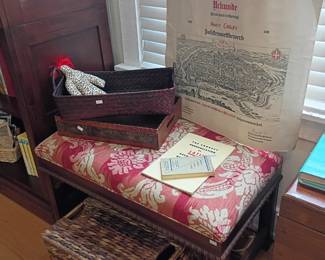 Wooden bench seat with floral cushion, dark wood bed frame headboard, books, bedroom furniture