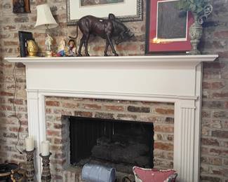 Fireplace mantel with framed art, bronze horse figurine, lamp, vases, brick surround decor