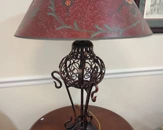 Wrought iron scrollwork table lamp, red floral fabric shade, ornate metal base accent lamp, round wood side table, vintage lighting decor