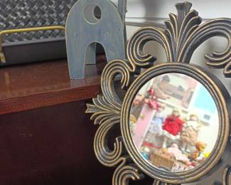 Decorative wall mirror, metal elephant figurine, and scrollwork decor