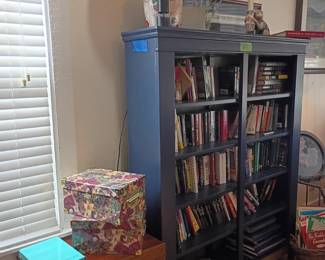 Blue painted bookshelf with books, gift wrap supplies, table lamp, storage furniture