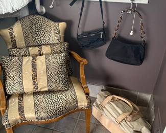 Armchair with accent pillows, purses and travel bag