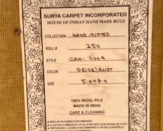 Label on back of area rug 100% wool pile, hand made in India, 62”, 95”