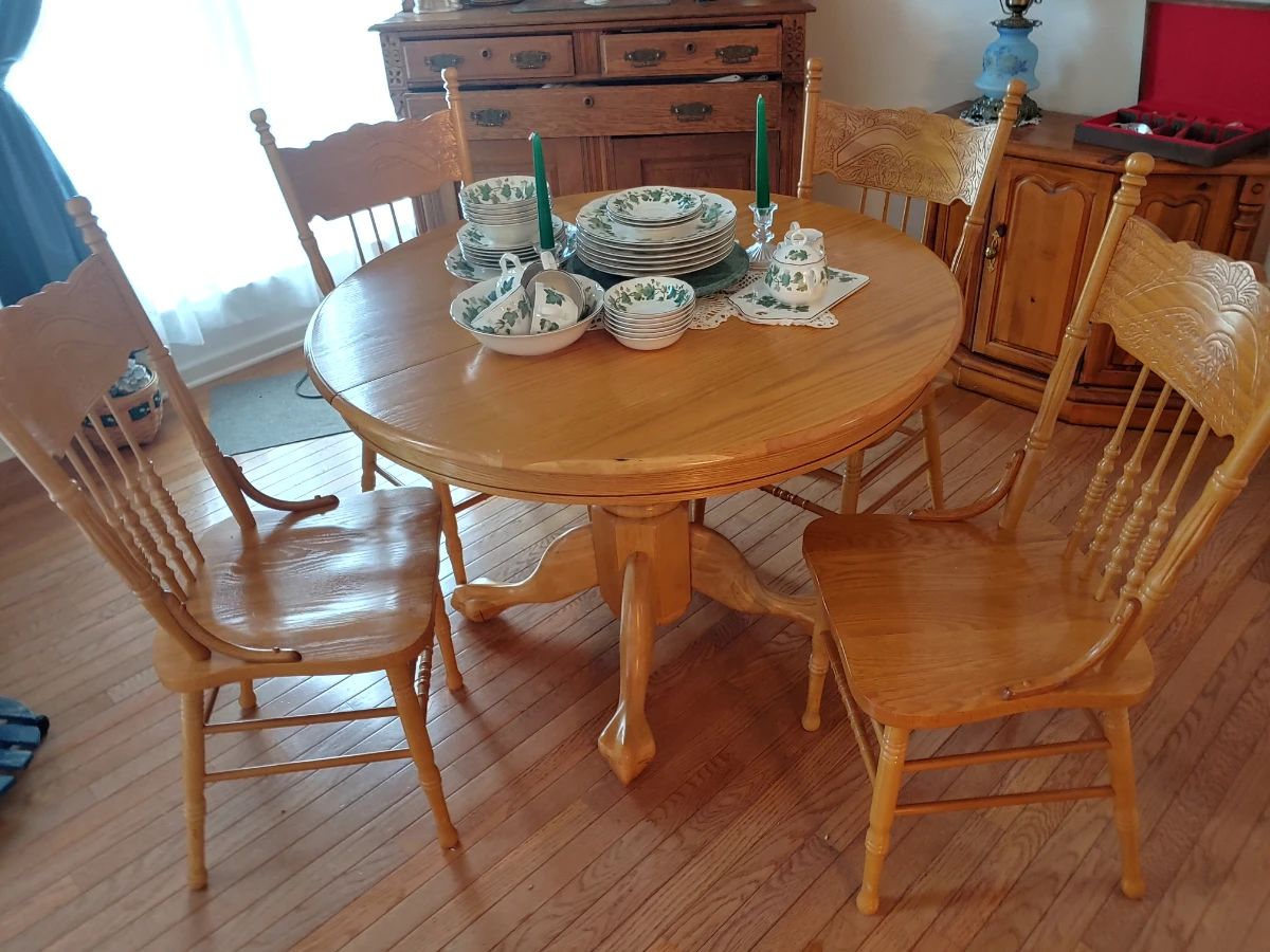 Round solid oak dining table with four matching chairs and leaf