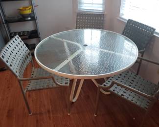 Outside round glass top patio table with four matching chairs