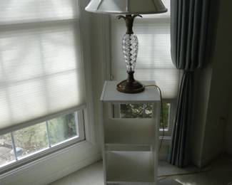 Tall brass and glass table lamp, balanced on a shelving unit