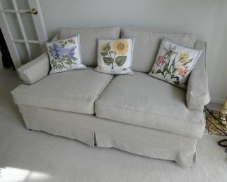 A very nice neutral couch with three floral print pillows