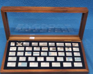 Lot 372. 1974 The Great Flags of America collection from the Franklin Mint of 42 sterling silver flag ingots weighing 210 grams and a book that provides the history of each flag.