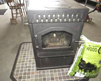 Lot 242. American Energy Systems pellet or corn stove, Model: BC-DC 8000-40000 BTU, includes fabricated base and 240 pounds of wood pellets. Very heavy, bring help to load.