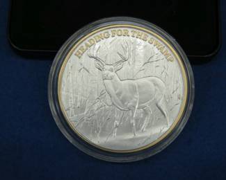 Lot 254. Les Kouba Tribute "Heading For The Swamp" Commemorative Coin. It is clad in .999 pure silver and selectively layered in 24k gold and has a total weight of 4.5 ounces.