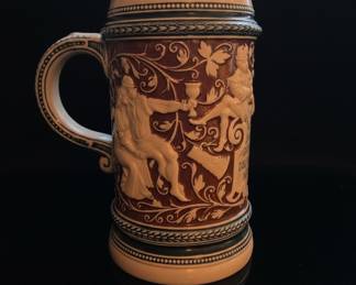 Collection of Three German Beer Steins: Relief Ceramic, Pewter-Lidded Embossed, and Cartoon-Style Ceramic