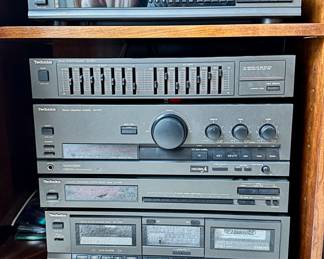 Vintage stacked audio electronics by Technics.  Includes turntable (not pictured), CD carousel, equalizer, integrated amplifier, AM/FM tuner and dual cassette player/recorder.