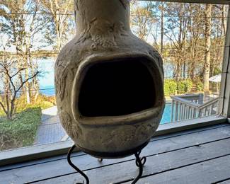 Clay chiminea on three-legged stand.