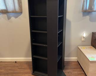 D66 - $40. Spinning storage cabinet. Measures 18.75" square x 50" tall. Black finish. Does have some chips in the veneer. Shelves are adjustable for books or CDs/DVDs. 