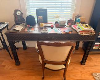 Antique dark wood writing desk with fretwork detail, upholstered armchair, mantel clock