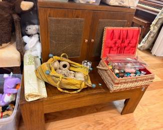 Wooden end table with sewing baskets, craft supplies, and collectibles