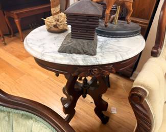 Victorian marble-top round parlor table with carved pedestal base, vintage hat box